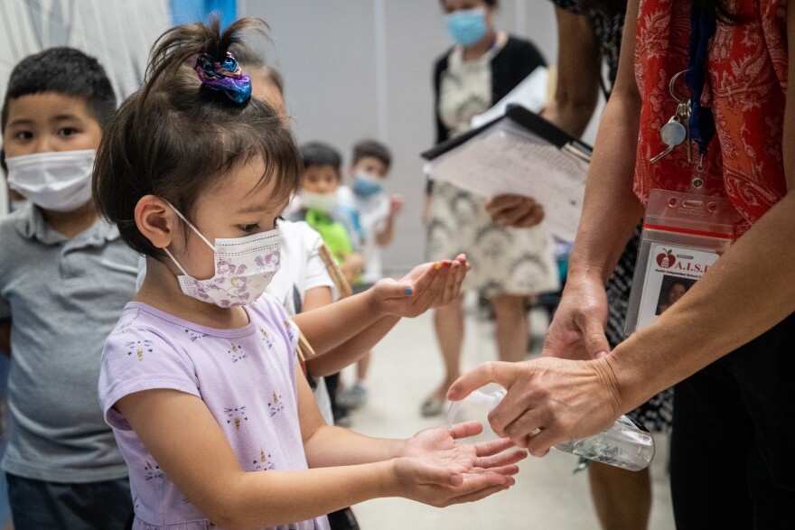 Pre-K student Aria Dang-Tran holds out her hands for hand sanitizer after finishing lunch at Summitt Elementary School in Austin on Aug. 26.