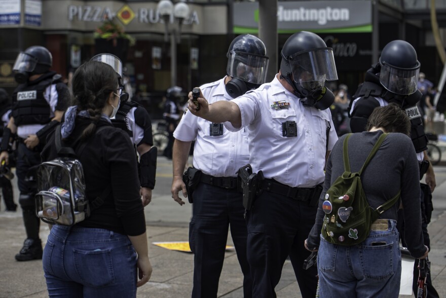 A Columbus Police officer aims a pepper spray cannister at a protester's face on May 30, 2020.