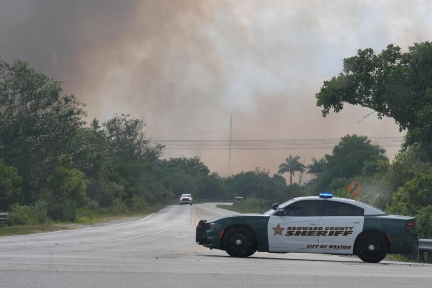 A Broward County Sheriff's police car blocks the entrance to a park as a wildlife burns in Broward County, Fla., Monday, May 11, 2026. (Marta Lavandier/AP)