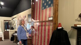 Kibbe Hancock Heritage Museum volunteer Joy Swearingen in front of a flag made in 1858 in honor of Abraham Lincoln. 