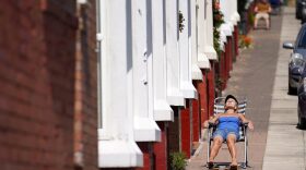 People enjoy the warm and sunny weather relaxing on the pavement outside their homes in the Shorefields area of Liverpool, United Kingdom. 