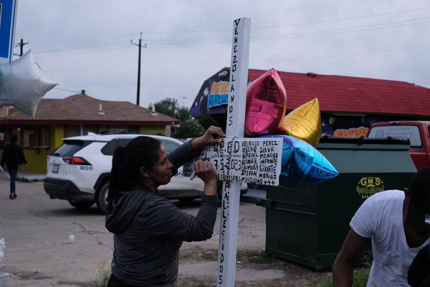 Marilin, mother of Hector David Medina-Medero, writes his name on a cross erected next to the Brownsville bus stop on Minnesota and Houston where a man plowed into migrants on Sunday, May 7.