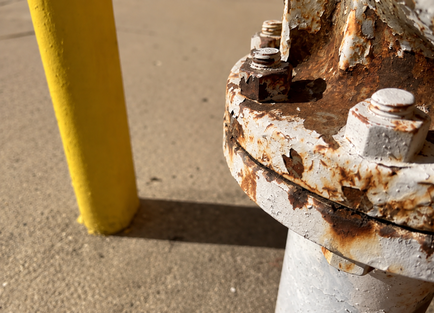 Picture of a white-ish colored gas meter with some corrosion. 