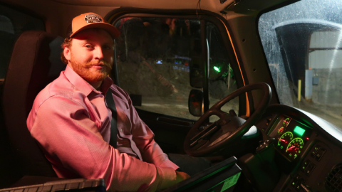 A man sits in the driver's seat of a snowplow.