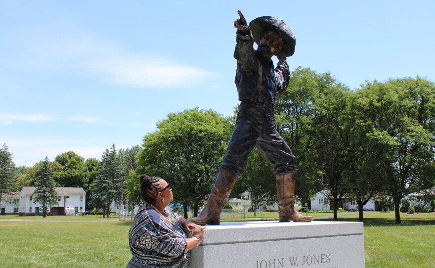 Talima Aaron, president of the board of trustees for the museum admires the lifelike bronze and brass statue of John W. Jones that she and the board envisioned and commissioned a few years ago.