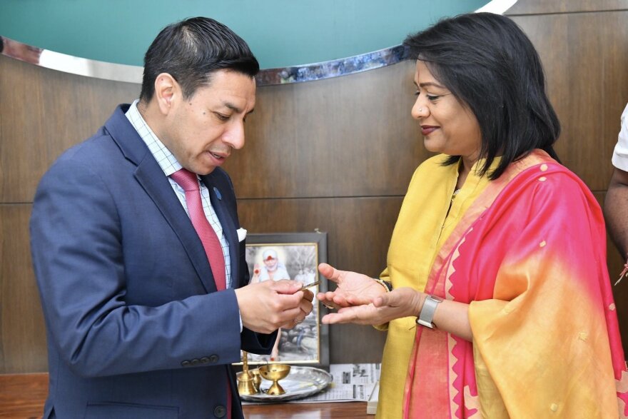 Secretary Diego Morales, left, holds a coin with an unnamed woman from India.