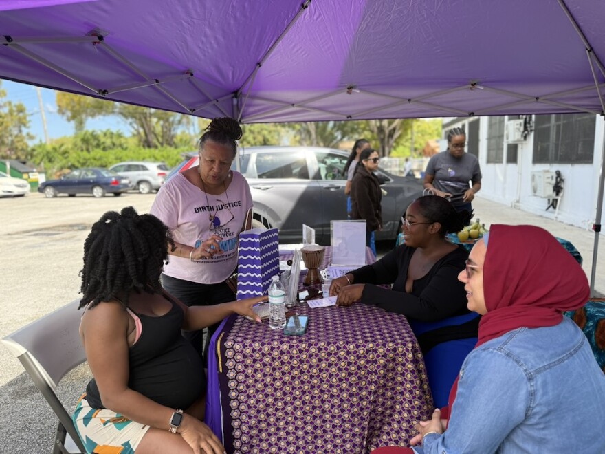 Doulas chat with patient Isis Daaga, seated left, at the mobile midwifery clinic’s booth in Miami at the Freedom Lab on March 21.