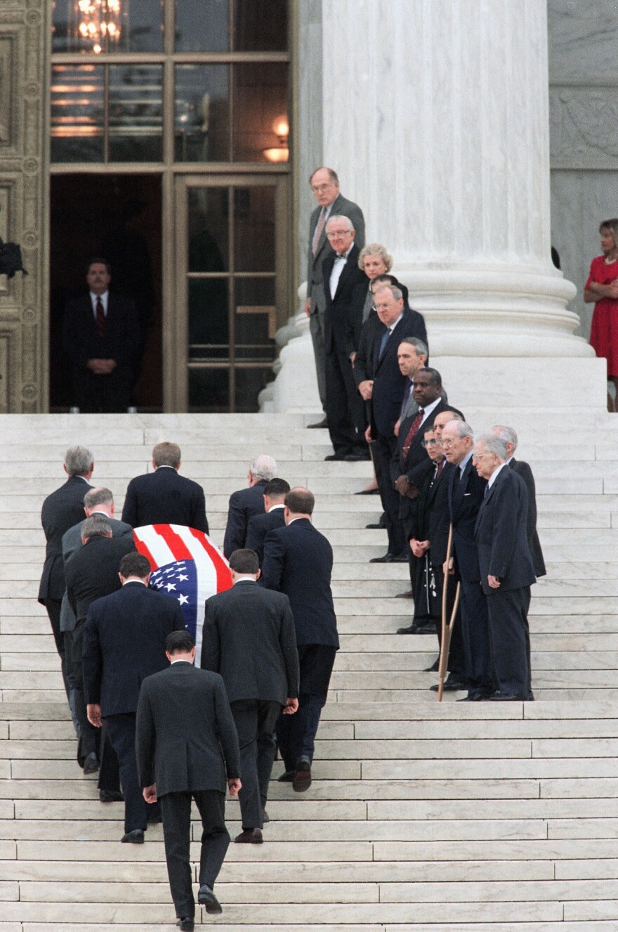 Past and present members of the Supreme Court, right, line the stairs as the coffin of retired Chief Justice Warren Burger is carried into the Court on in June 1995.