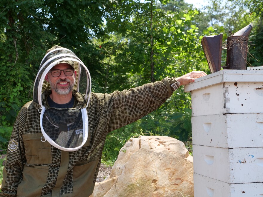 Adam Hickman, the lead beekeeper at Foxhound Bee Company, stands next to some of his hives.