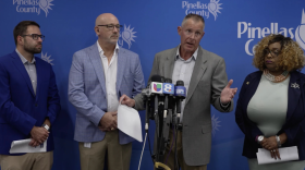 El comisionado del condado, Brian Scott, se encuentra en un podio mientras responde preguntas de la prensa.