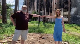man holds woman hand by burnt building