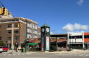 A green clocktower stands on a street corner