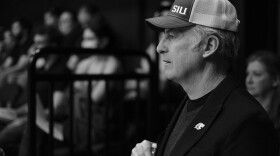 A black and white image of Bob Odenkirk wearing an SIU hat during a speaking engagement at SIU