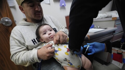 Cesar Acevedo, left, holds his infant son, Adriel Acevedo, as as nurse Tracey McElroy, right, prepares to give him a vaccination that included a polio dose at the Dallas County Health and Human Services immunization clinic in Dallas, Friday, April 4, 2025.