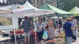 Patrons of the market walk between tents with flowers and produce, June 14, 2022.