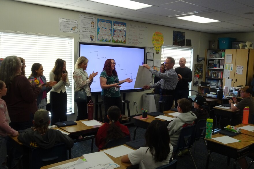 Director of operations in Wasatch County Schools, Shawn Kelly, presents Brandi Leavitt, center, with a $10,000 check for personal use, recognizing her as one of the district's 2026 Distinguished Educator.