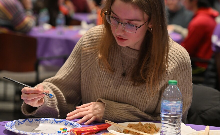 Haley Fahey, a freshman at the University of Scranton, practices picking up M&Ms with chopsticks.