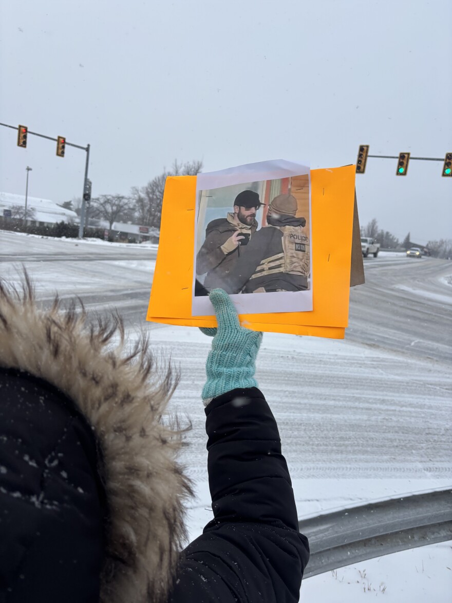 A protester in Michigan holds a photo of 37-year-old Alex Pretti taken just before he was fatally shot by ICE agents
