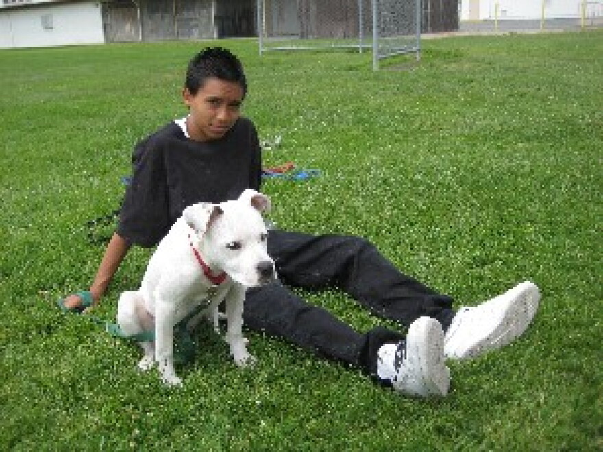 8th grader Alex Arzeta sits with his dog Fifi after a training session.