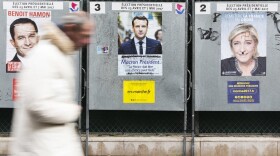 A man walks past electoral posters displaying the presidential candidates, Benoit Hamon, left, Emmanuel Macron, center, and Marine Le Pen in Paris, France. (Kamil Zihnioglu/AP)