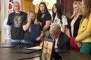 Gov. Mike DeWine signs an order recognizing National Childhood Cancer Awareness Month, with the Zurlinden family to his left.