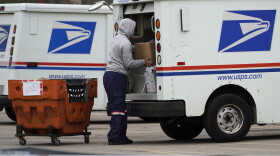 A USPS employee loads a truck outside post office in Wheeling, Ill., Friday, Dec. 3, 2021.