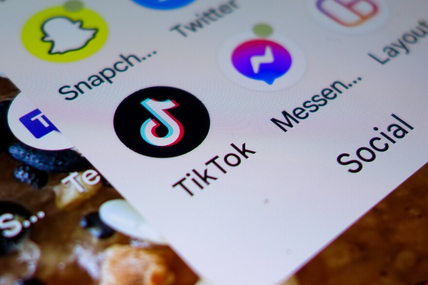 The TikTok logo on a smartphone screen. Other apps visible are Snapchat, Twitter and Facebook Messenger.