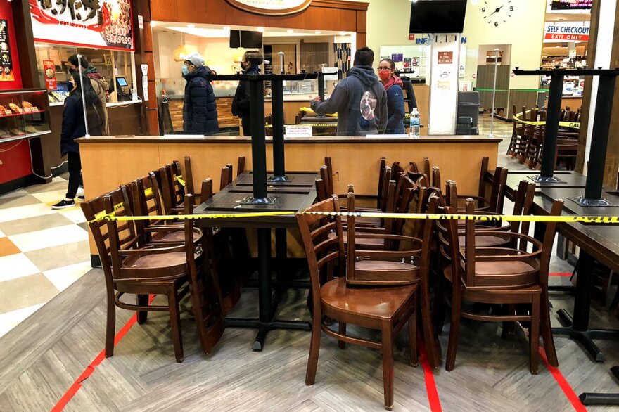 The seating area is closed-off due to coronavirus restrictions at a food court, as customers line up for take-out food in a grocery store in Arlington Heights, Ill., on Friday, Nov. 13, 2020.