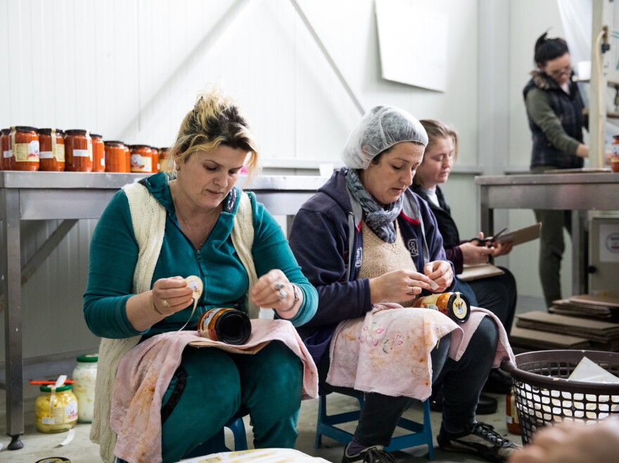 Women, most of them widows, work in the factory, labeling pepper jars by hand.