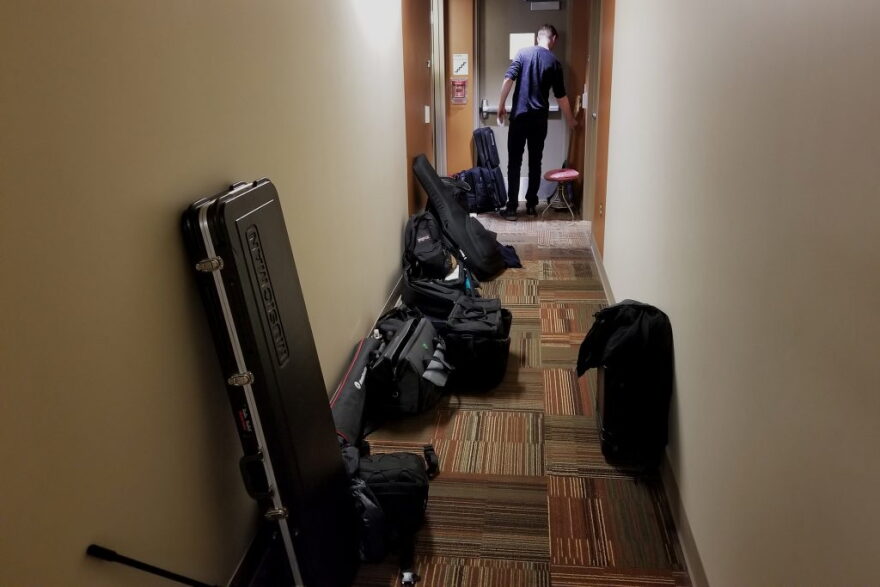 A tight hallway is packed with equipment cases just outside of the room where the concert happens.