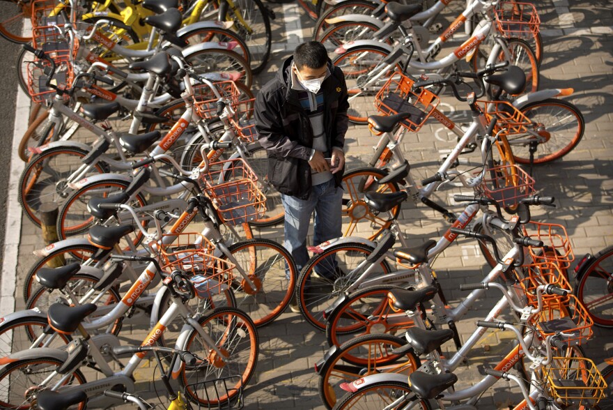 A man prepares to unlock a Mobike shared bicycle parked along a street in Beijing.