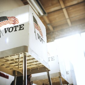An empty polling site. There are three voting cubicles placed in a row.