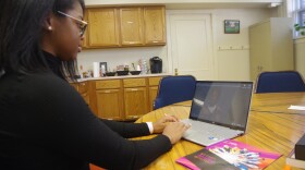 Chianté Lymon, S.H.A.R.E.’s executive director, sits at a conference table reviewing an oral history in the organization's office in Kalamazoo. She's wearing a black turtleneck sweater. 