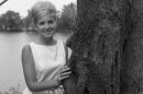 A photo of young Charlotte Thompson Suhler in the 1960s by a tree in front of a lake.