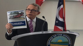 Gov. Mike DeWine holds up a copy of the report on distracted driving in Ohio.