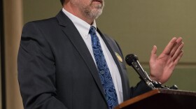 A white man speaks at a podium