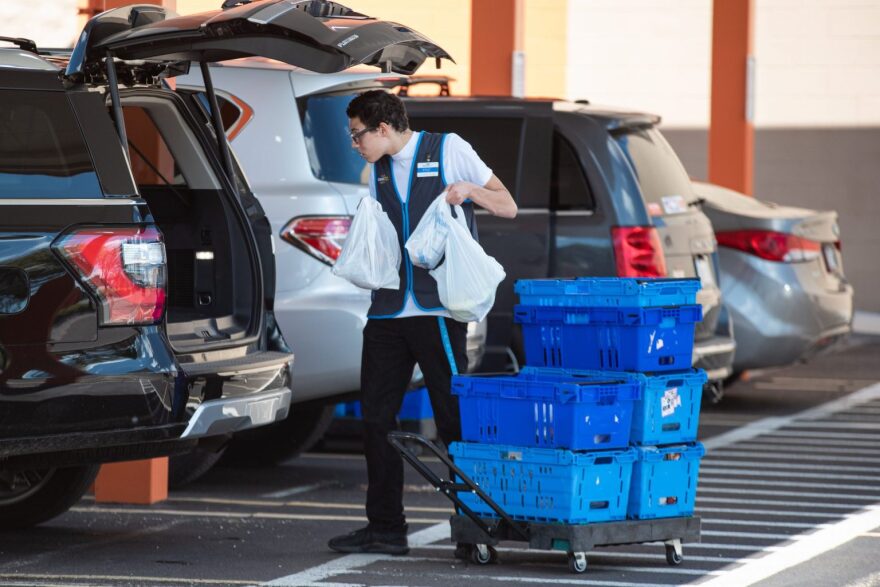 A Norman Walmart employee loads a pick-up order into the back of a car on March 24.