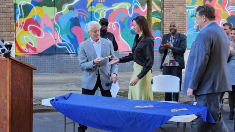 Niagara Falls Mayor Robert Restaino offers a ceremonial key to Ally Spongr, Director of Public Art for Niagara Falls National Historic Area, in recognition of NFNHA's commitment to refurbish one of the city's old churches, part of a project revitalizing Main Street buildings.