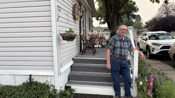 Man stands in front of a white house.