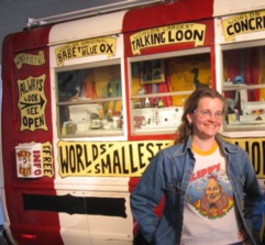 Artist Erika Nelson standing in front of "World's Largest Collection of the World's Smallest Versions of the World's Largest Things"