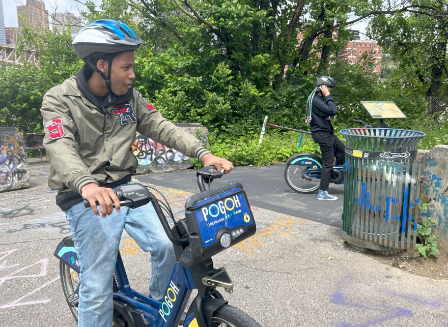 Teens sit on electric POGOH bikes on trail with graffiti