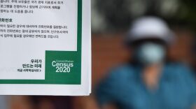 A volunteer displays information in Korean encouraging people to complete the US Census, at a food distribution bank for people facing economic hardship or food insecurity in a church parking lot in Los Angeles, California.