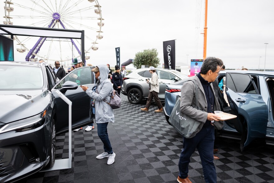 Lexus employees and attendees of the Electrify Expo, a showcase of new electric cars, trucks, bikes and scooters, explore various electric and hybrid Lexus vehicles 