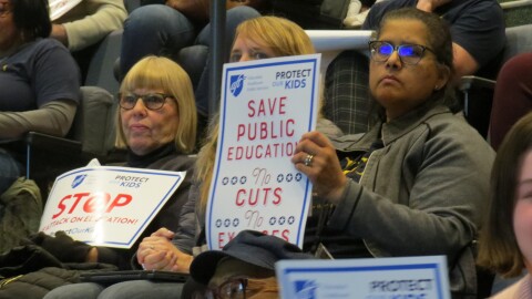 Cincinnati Public School teachers hold signs during a 2025 Board of Education meeting.