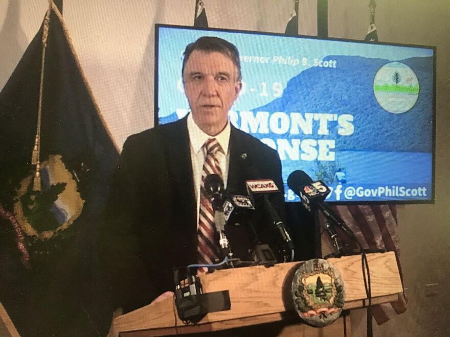 Gov. Phil Scott stands at a podium next to a screen