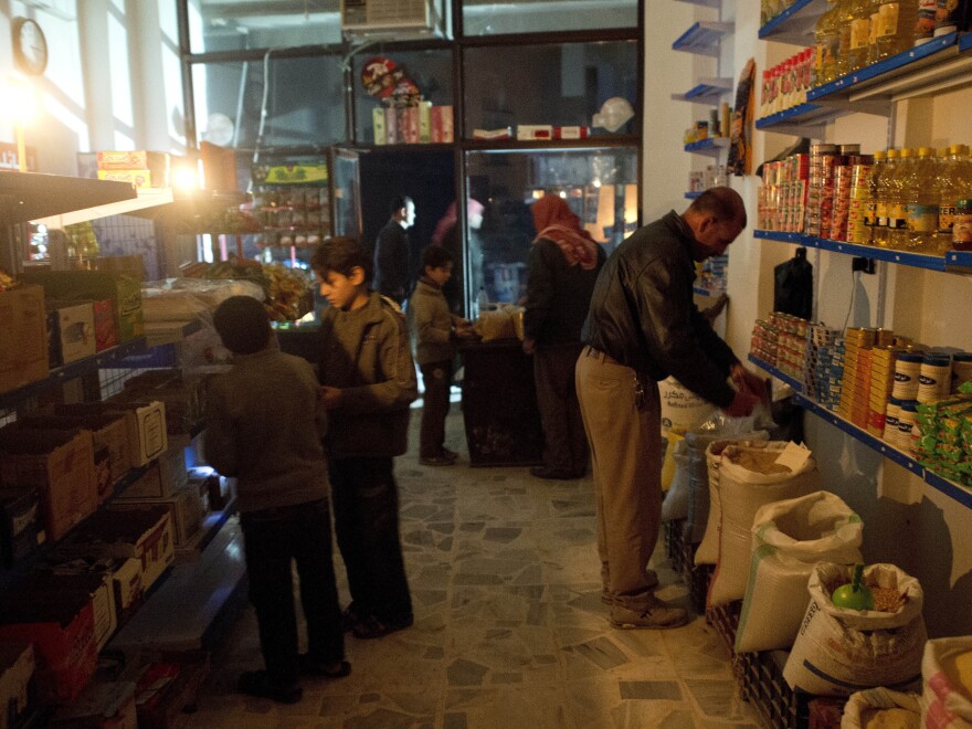 Customers shop by candlelight in a grocery store in Aleppo. The city has been hit hard by fighting in recent months, with both the opposition and the government controlling parts of the area.