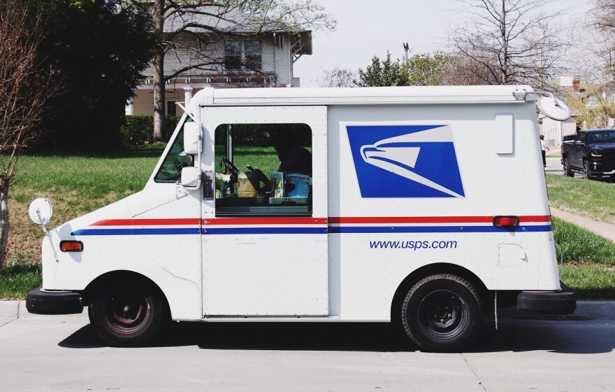 Postal service truck in a neighborhood with boxes of mail next to the driver