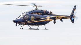 A blue and gold Delaware State Police helicopter in flight