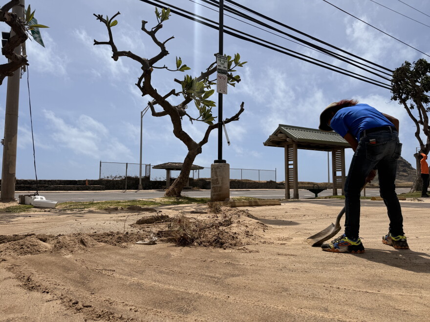 Teresa Salva, 68, Wai’anae resident, helps clear sand from Hurricane Lowell's high surf along Farrington Highway. She and other residents say they've never seen the water go over to this part of town.