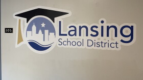 An image of the Lansing School District logo with a graduation cap and a white silhouette of the city skyline.